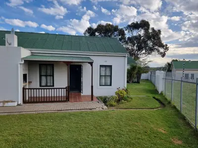 a white house with a green roof and a fence at Strawberry fields Tranquility in Cape Town