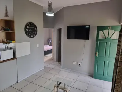 a living room with a green door and a television at Strawberry fields Tranquility in Cape Town