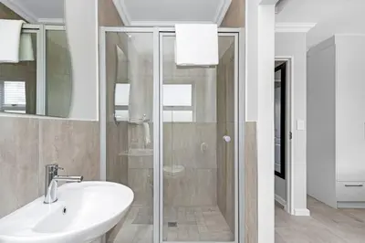 a bathroom with a glass shower and a sink at Elegant, Spotless 2 Bed For Enchanted Stays in Cape Town
