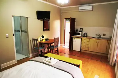 a room with a bed and a kitchen with a table at Casa Mia Guesthouse in Table View