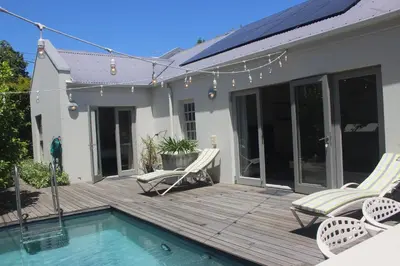 a deck with two chairs and a swimming pool at Leopard Tree Cottage in Franschhoek
