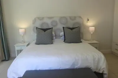 a bedroom with a large white bed with two lamps at Leopard Tree Cottage in Franschhoek