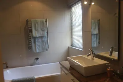 a bathroom with a sink and a tub and a mirror at Leopard Tree Cottage in Franschhoek