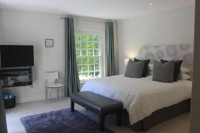 a bedroom with a large bed and a window at Leopard Tree Cottage in Franschhoek