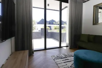 a living room with a couch and a large glass door at Modern apartment in Century City in Cape Town