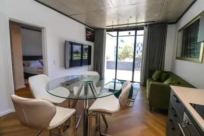 a living room with a glass table and white chairs at Modern apartment in Century City in Cape Town