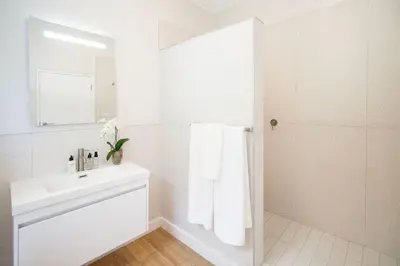 a white bathroom with a sink and a mirror at Middedorp Apartments in Stellenbosch