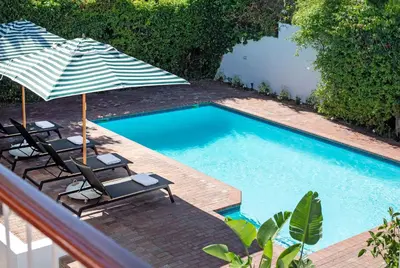 two chairs and umbrellas next to a swimming pool at Middedorp Apartments in Stellenbosch