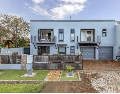 a white house with a fence and a yard at The Elephant Cottage in Cape Town