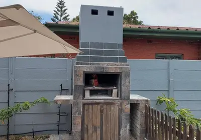 a outdoor pizza oven in front of a building at The Elephant Cottage in Cape Town