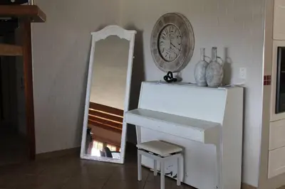 a white piano with a clock and a mirror at Firlands Farmhouse 179A with a view in Sir Lowry Pass