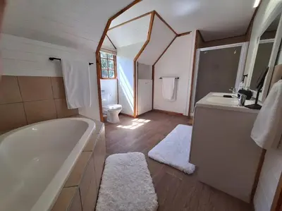 a bathroom with a tub and a sink and a mirror at Firlands Farmhouse 179A with a view in Sir Lowry Pass