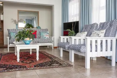 a living room with white chairs and a table at Casa Familia in Hermanus