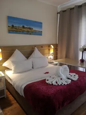 a bedroom with a bed with white sheets and pillows at Coastal Cozy 2 in Cape Town
