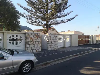 a car parked in front of a fence with a tree at Coastal Cozy 2 in Cape Town