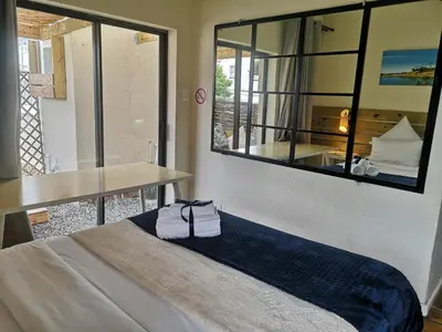 a room with a bed and a table and a mirror at Coastal Cozy 2 in Cape Town