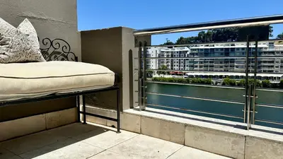 a bed on a balcony with a view of a city at Meerendahl Luxury Apartments at Tyger Lake in Cape Town