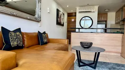 a living room with a couch and a table at Meerendahl Luxury Apartments at Tyger Lake in Cape Town