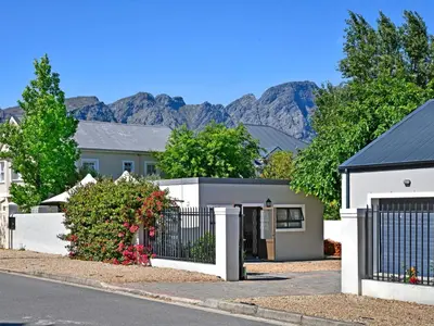 a house with a fence and mountains in the background at La Rochelle Cottage in Franschhoek