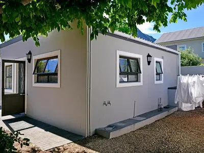 a white house with a door and a clothesline at La Rochelle Cottage in Franschhoek