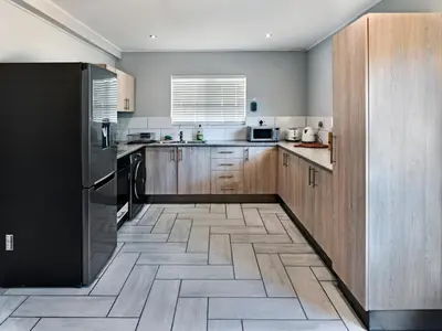a kitchen with wooden cabinets and a black refrigerator at La Rochelle Cottage in Franschhoek