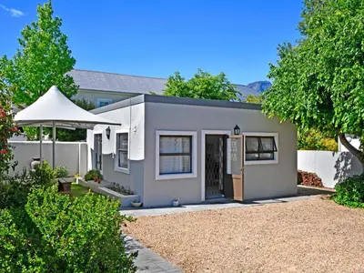 a gray house with a fence and a yard at La Rochelle Cottage in Franschhoek