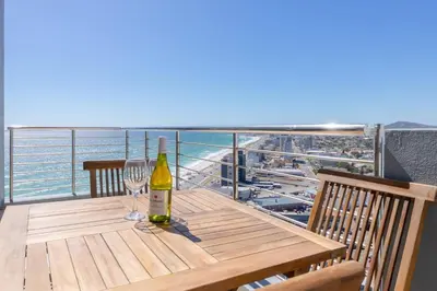 a table with a bottle of wine and glasses on a balcony at Horizon Bay 1603 by HMH in Cape Town