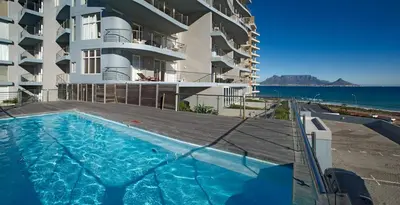 a swimming pool in front of a building with the ocean at Horizon Bay 1603 by HMH in Cape Town