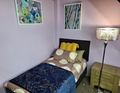 a small bedroom with a bed and a lamp at Amatoni green apartment in Stellenbosch
