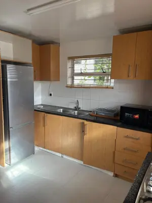 a kitchen with wooden cabinets and a stainless steel refrigerator at Harmony Lawson Road in Cape Town