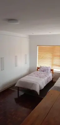 a white bedroom with a bed and a window at Harmony Lawson Road in Cape Town