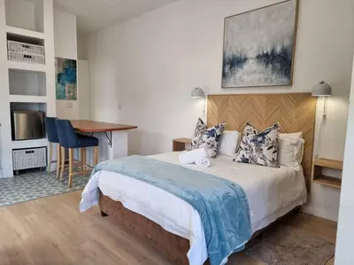 a bedroom with a bed and a desk and a table at @5 on Lincoln in Cape Town