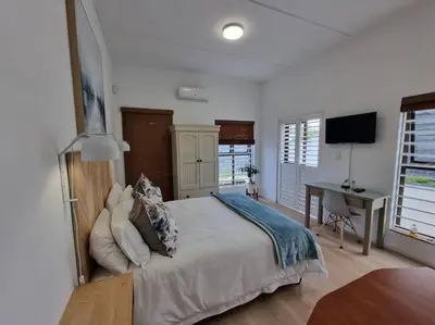 a bedroom with a bed and a desk with a computer at @5 on Lincoln in Cape Town