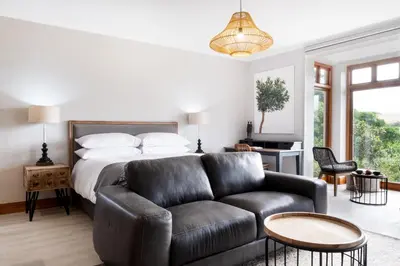 a bedroom with a bed and a leather couch at Avemore Manor House wood fired hot tub magical views and full Backup power in Stellenbosch