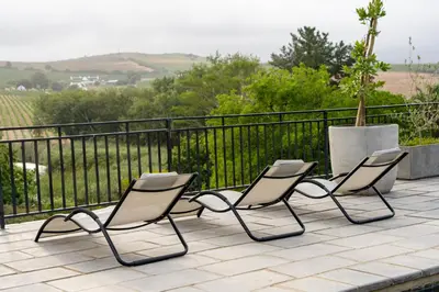 three chairs sitting on a patio with a fence at Avemore Manor House wood fired hot tub magical views and full Backup power in Stellenbosch