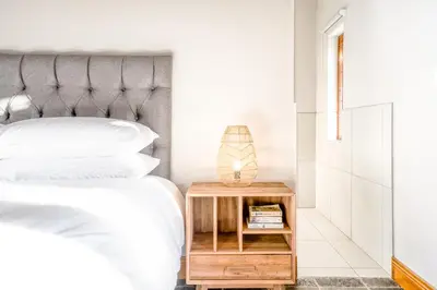 a bedroom with a bed and a nightstand with a lamp at Avemore Manor House wood fired hot tub magical views and full Backup power in Stellenbosch