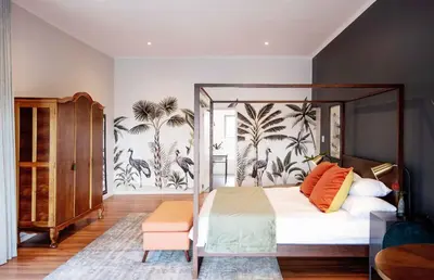 a bedroom with a canopy bed with a tropical wallpaper at Fransmanskraal Accommodation - Luxury Stellenbosch Farm Villa in Stellenbosch