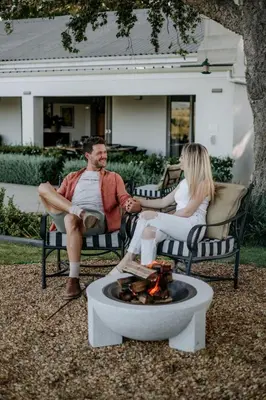 a man and woman sitting in chairs around a fire pit at Fransmanskraal Accommodation - Luxury Stellenbosch Farm Villa in Stellenbosch
