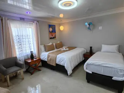 a bedroom with two beds and a chair and a window at Essential Lodge23 in Cape Town