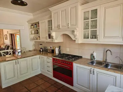 a kitchen with white cabinets and a red stove top oven at Valley View Eco Country Estate - Paradise in the Winelands in Villiersdorp