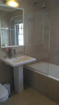 a bathroom with a sink and a tub and a mirror at Evertsdal Guesthouse in Durbanville