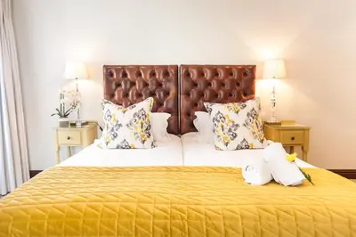 a bedroom with a large bed with yellow sheets and pillows at Evertsdal Guesthouse in Durbanville
