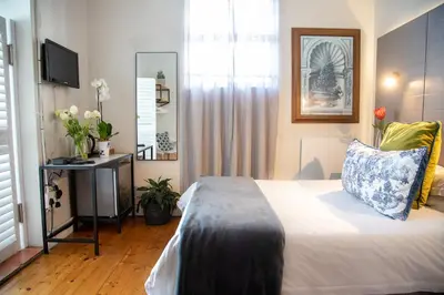 a bedroom with a bed and a television and flowers at Loddey's Guesthouse by Beach Collection Winelands in Strand