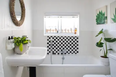 a white bathroom with a sink and a bath tub at Loddey's Guesthouse by Beach Collection Winelands in Strand