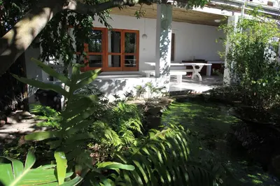 a garden with a house with a porch and a patio at Haven of Peace and Garden Cottage in Hermanus