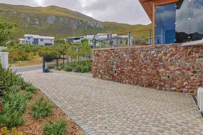 a stone walkway next to a stone wall at The View, Apartment, with magnificent sea view in Hermanus