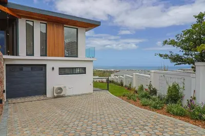 a house with a driveway leading to a garage at The View, Apartment, with magnificent sea view in Hermanus
