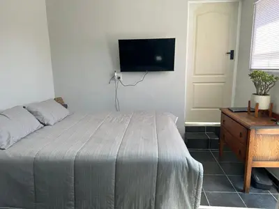 a bedroom with a bed and a tv on the wall at Ruach 5 in Cape Town