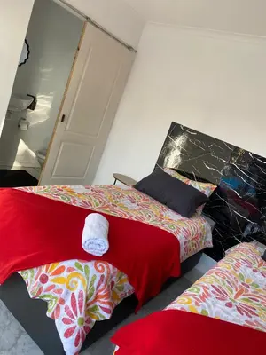 a bedroom with two beds with red sheets at Stay at Gabby's- no loadshedding in Cape Town