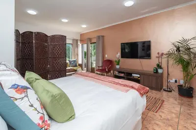 a bedroom with a large white bed and a flat screen tv at Apartment in Milnerton close to Woodbridge Island in Cape Town